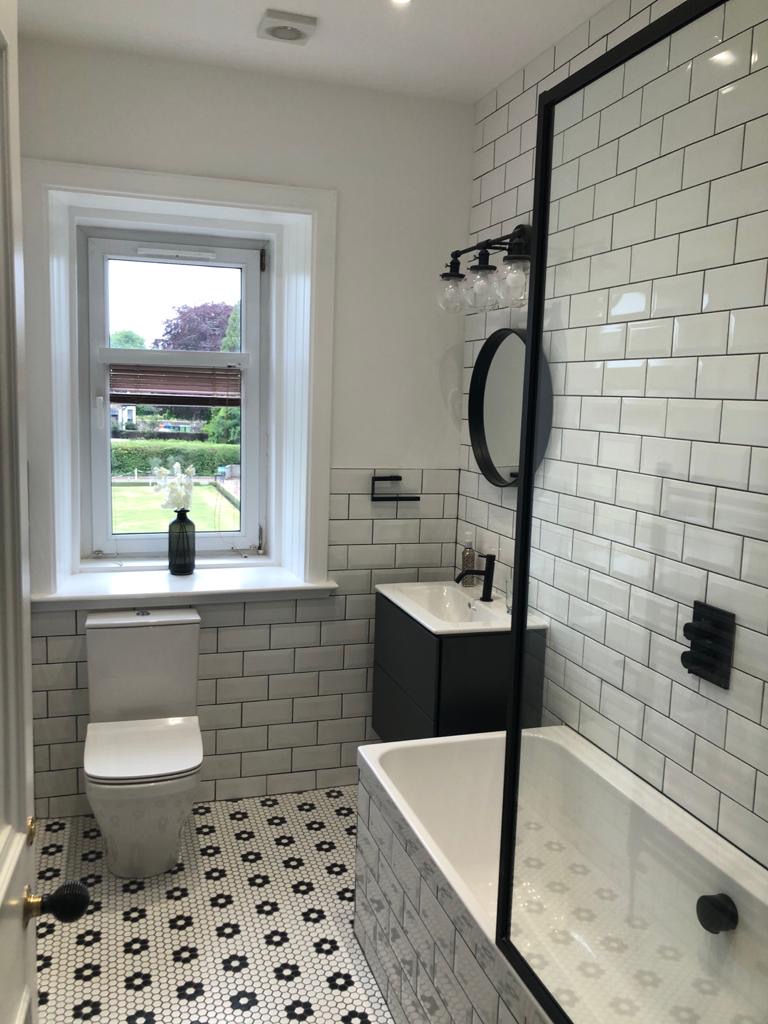 Modern bathroom with white subway tiles, black fixtures, and patterned floor tiles