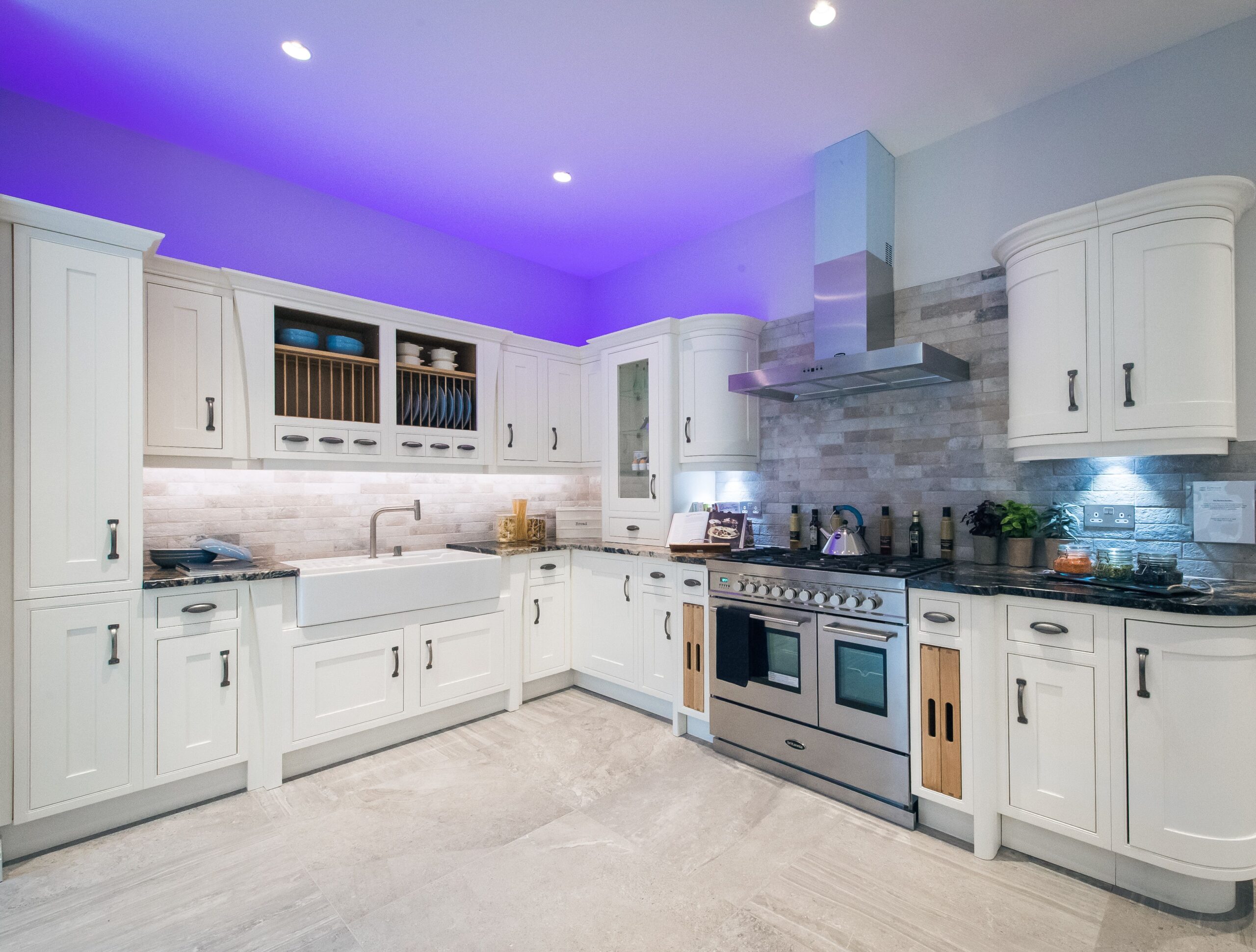 Contemporary kitchen with white cabinets, purple LED lighting, and modern appliances