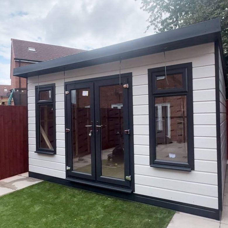 Bespoke garden room with white cladding and black-framed bi-fold doors